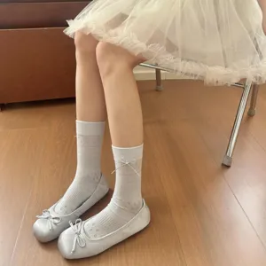 Detail shot of sweet bow mid-tube socks paired with silver ballet flats and white skirt.