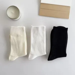 Detailaufnahme von einfarbigen Socken in Creme, Weiß und Schwarz, ordentlich flachgelegt.