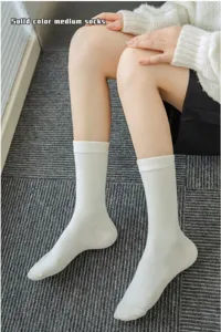 Detailed view of white mid-calf socks worn by model, showing clean ribbed fabric design.