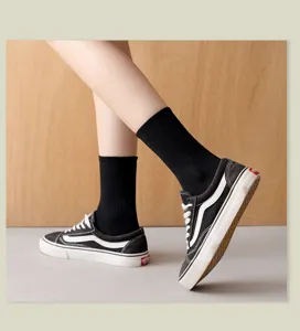Detail shot of solid black mid-calf socks paired with classic canvas shoes, soft fabric.