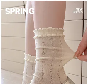 Detailopname die de rekbare textuur en de delicate geroesde manchet van de damessokken toont.