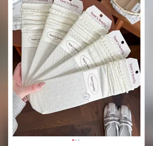 Gedetailleerd overzicht van witte katoenen sokken met kanten rand en merkverpakkingskaart voor dames.