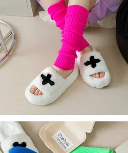 Gemütliche Strickstulpen und flauschige Plüschhausschuhe mit stilvollem Kreuz-Design.