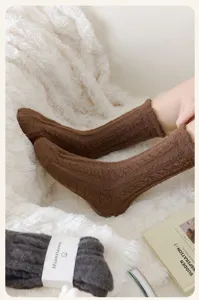 Cozy brown plush cable knit warm socks detail shot on white fluffy blanket background