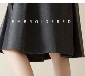 Detailed view of dark grey pleated fabric with embroidered design, elegant style.