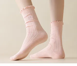 Close-up detail of women's pink ruffle knit mid-tube socks with cute bow embroidery design.
