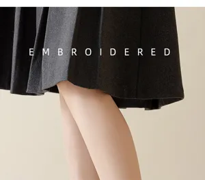 Close-up detail view of pleated skirt fabric texture with stylish embroidered English text.