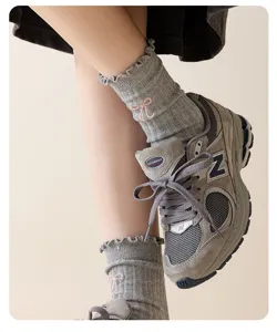 Detailed shot of grey women's mid-tube cotton socks featuring cute pink bow embroidery and ruffles.
