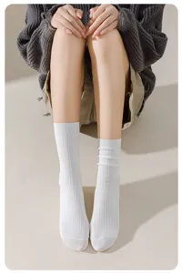 Close-up detail shot of casual women's white ribbed crew socks worn by a seated model.