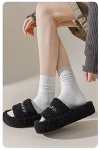 Detailed view of comfortable white ribbed cotton socks paired with black plush fluffy slide slippers.