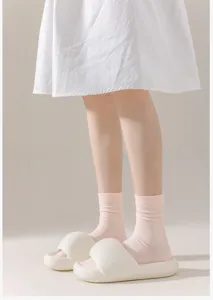 Close-up detail view of comfortable pink cotton mid-tube socks paired with casual slides.