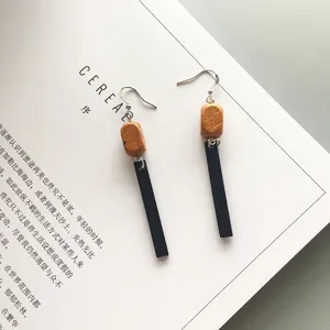 Detail view of long geometric wooden dangle earrings displayed on a minimalist magazine background