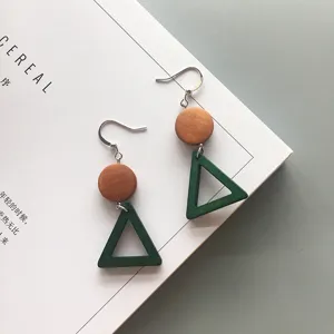 Close-up detail of geometric green triangle and brown round wood drop earrings texture