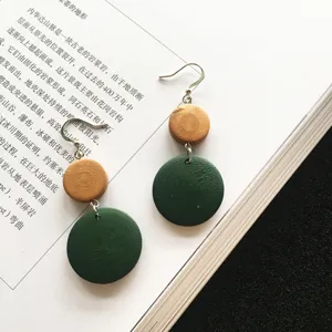 Detail of handcrafted geometric wooden earrings in yellow and forest green colors.