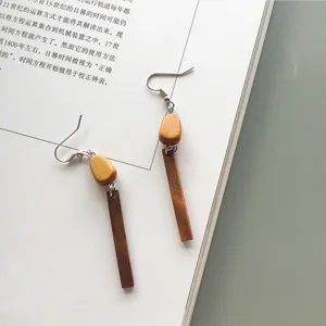 Detailed shot of minimalist geometric long wooden strip earrings on magazine backdrop