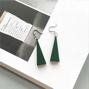 Detailed close-up of dark green triangular wooden earrings on magazine background