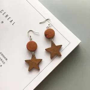 Close-up detail of handmade wooden star earrings displayed on a minimalist magazine surface