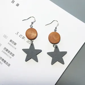 Close-up detail of stylish handmade wooden star and circle drop earrings with natural texture.
