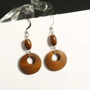 Detailed macro view of geometric hollow wooden earrings with silver hooks
