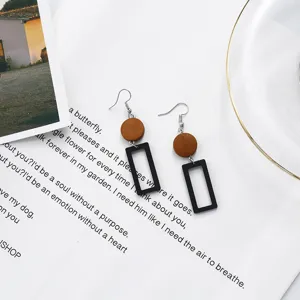Close-up of geometric wooden earrings with black hollow frames on a white background.
