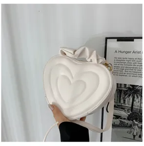 Close-up of a stylish white heart-shaped crossbody bag with elegant ruffled handle detail