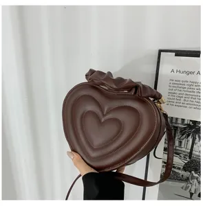 Macro detail of brown heart-shaped bag with layered stitching and ruffled handle