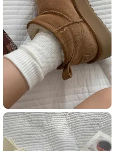 Detailed view of cozy wool knit stack socks in milk white worn with winter boots, soft texture.