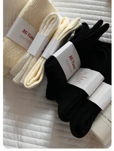 Cozy thick wool stack socks detail view in cream and black with branded packaging.