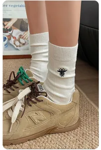Chaussettes mi-hautes blanches côtelées chic avec broderie abeille noire pour femmes.