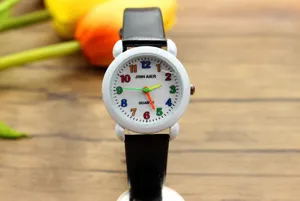 Kinder Quarzuhr Detail mit weißem Zifferblatt, bunten Zahlen und schwarzem Lederarmband.
