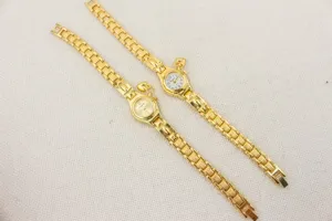 Primer plano detallado del reloj de pulsera dorado para mujer con colgante de corazón.