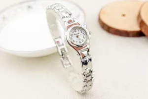 Vista detallada de reloj de pulsera de cuarzo para mujer plateado con correa metálica.