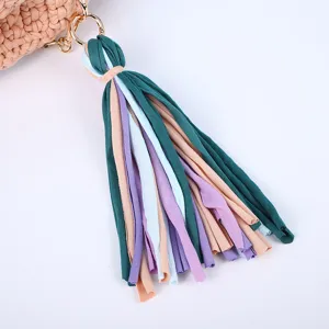Handmade crochet crossbody bag with colorful fabric tassel charm, stylish versatile women accessory.