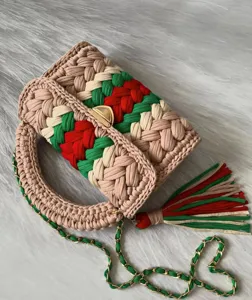 Handmade crochet shoulder bag detail, vibrant red green stripe color block design, chic tassel.