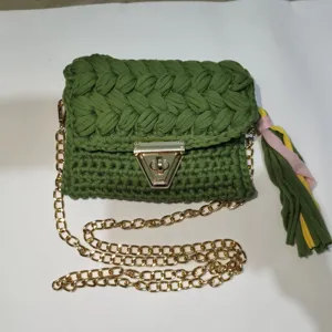 Handmade crochet phone bag detail, green knitted crossbody purse with gold chain tassel.