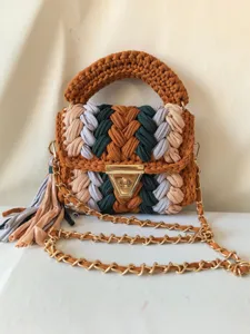 Handmade chunky knit crossbody bag detail, featuring multi-color braided yarn and gold hardware.