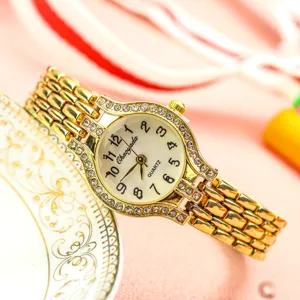 Gros plan de la montre quartz dorée ornée de strass brillants et chiffres clairs.