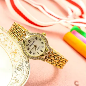 Gros plan sur les details de montre quartz dore strass, bracelet metal elegant femme.