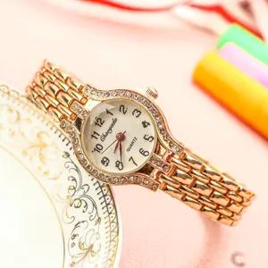 Gros plan détaillé d'une montre quartz femme en or rose avec strass et chiffres clairs.