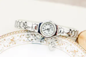 Detalle de reloj de cuarzo para mujer con delicada pulsera plateada y dije de corazón.