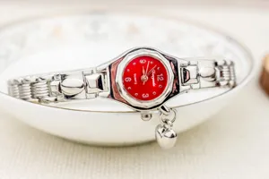 Elegante reloj de pulsera de cuarzo para mujer con esfera roja y bonito colgante.