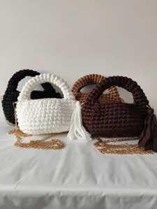 Handcrafted woven crossbody bag detail showing texture, metal chain, and stylish tassel accent.