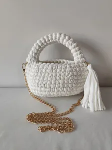 Close-up detail of white handmade crochet woven crossbody bag with gold chain strap tassel.