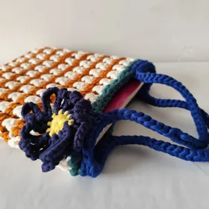 Handgemaakte gehaakte shopper met oranje-wit ruitpatroon en blauwe bloemenhandvat.