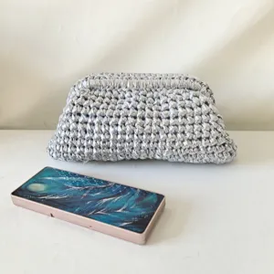Detailed view of silver crochet clutch bag, handmade woven ribbon texture, stylish accessory.