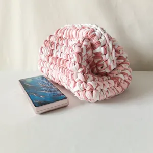 Closeup view highlighting the texture of handmade pink and white crochet t-shirt yarn clutch.