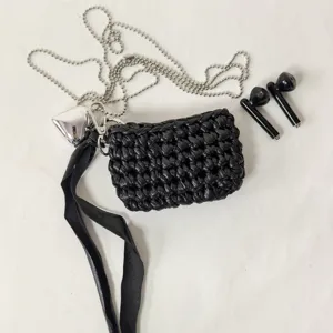 Detailed view of black handmade woven earphone pouch with silver chain and heart charm.