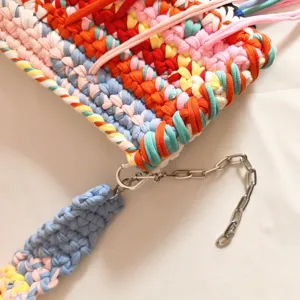 Detailed view of colorful crochet fabric strip women shoulder bag texture and metal chain link.