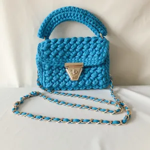 Handmade knitted blue crossbody bag with metal chain strap and stylish twist lock closure.