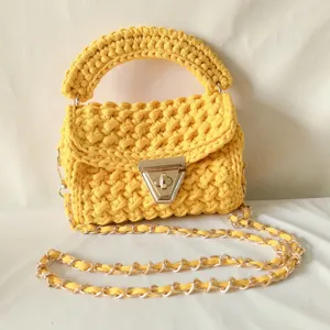 Handmade crochet shoulder bag with metal chain strap and twist lock closure in bright yellow.
